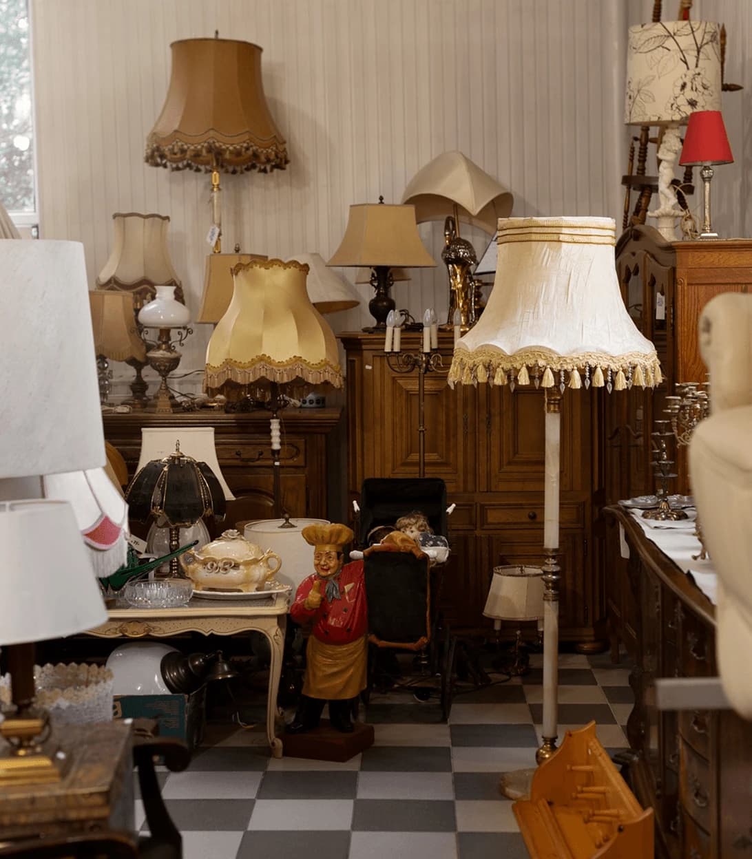 Antique warehouse with lamps, mirrors, and furniture awaiting collection.