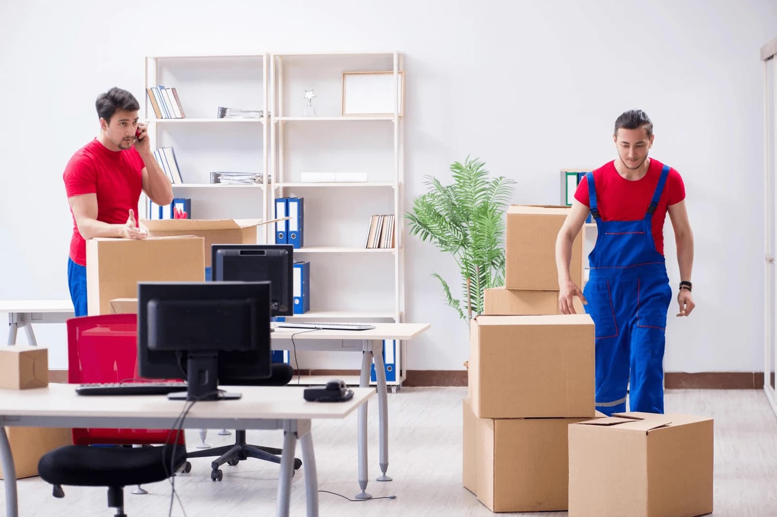 Operations team member coordinating logistics at a desk surrounded by moving boxes