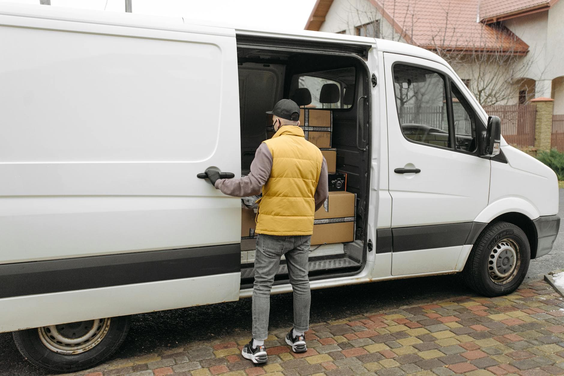 Delivery driver loading packages into a white removal van